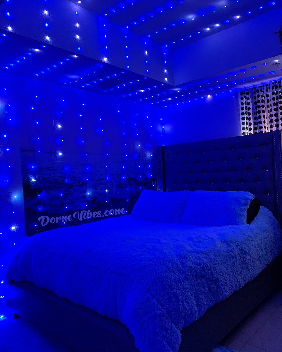 Blue ceiling light strands above a bed with a black headboard