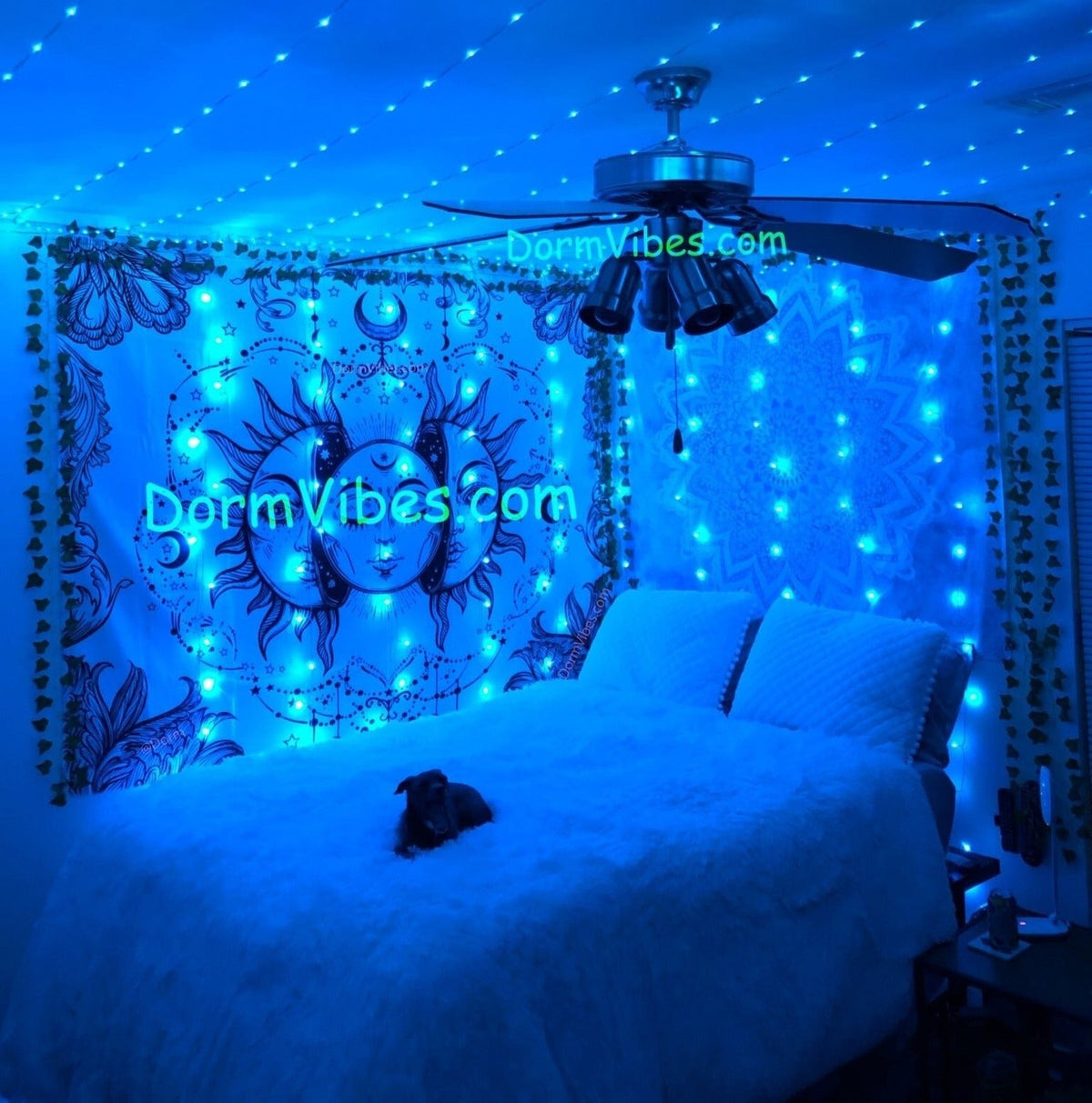 Blue ceiling light strands around a fan above a celestial tapestry
