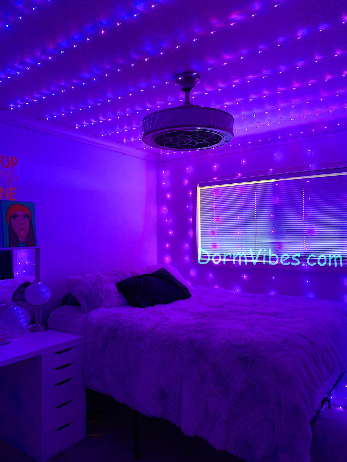 Purple ceiling lights around a round pendant above a fluffy bed
