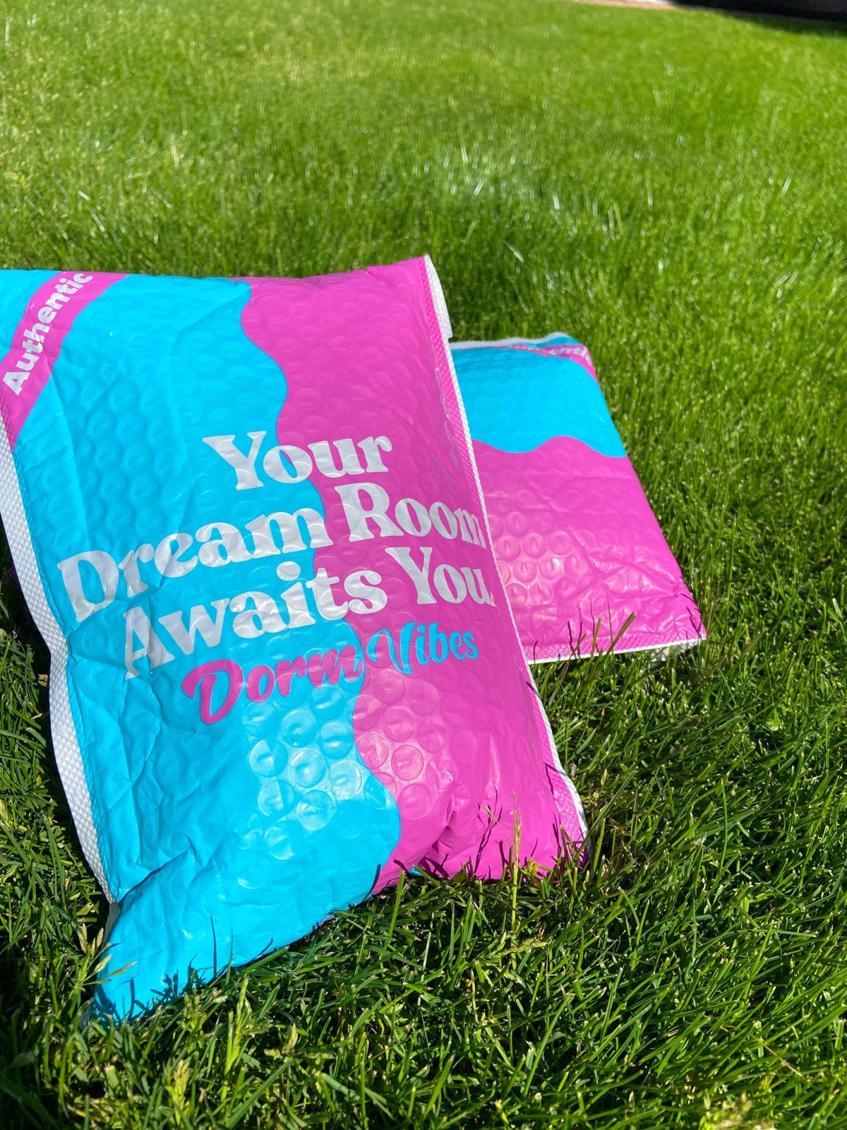 Turquoise and pink DormVibes mailing packages on a lawn