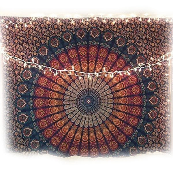 Orange and blue peacock mandala tapestry hung with white string lights