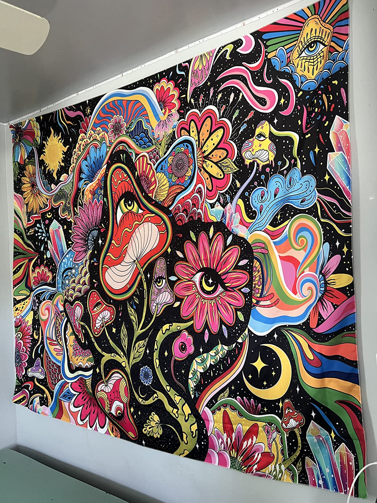Angled view of colorful mushrooms and flowers on a black wall tapestry