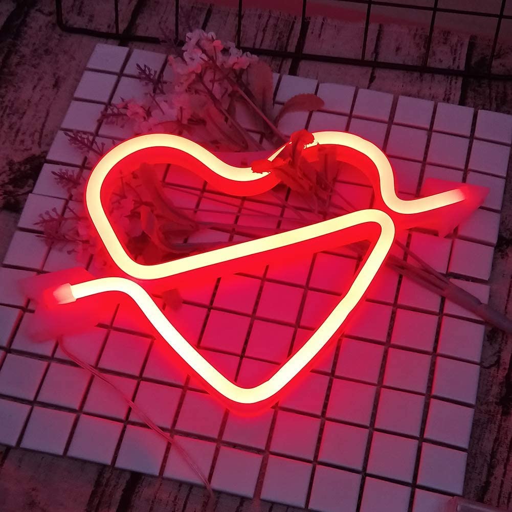 Red heart-and-arrow neon sign displayed on a wire grid