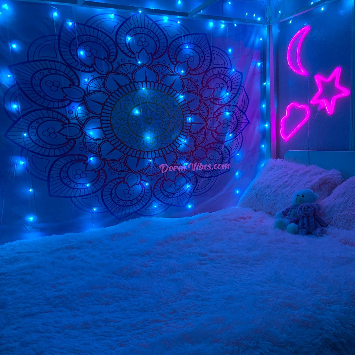 Pink moon, star and cloud signs beside a blue-lit bed