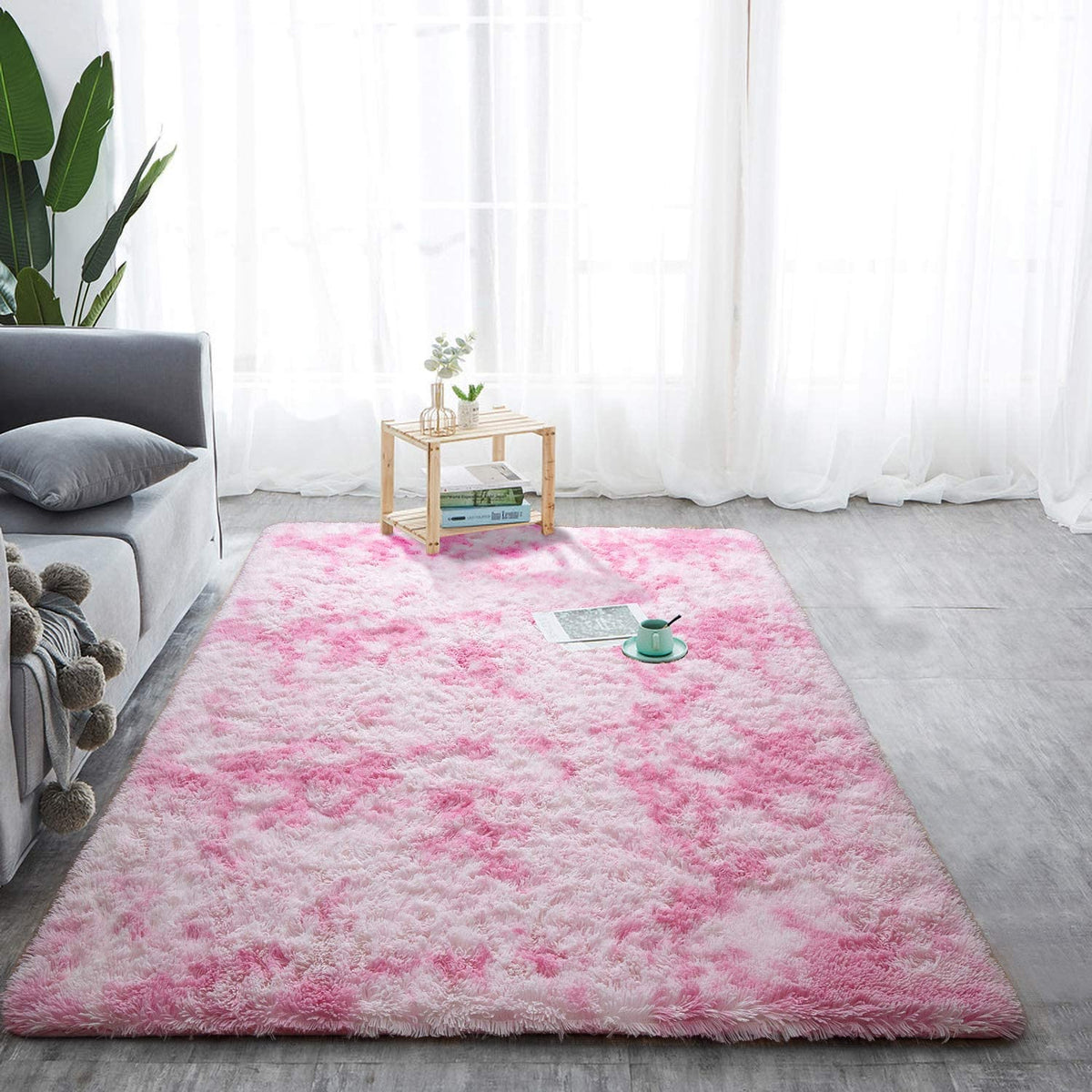 Pink and white tie-dye rug beside a sofa and small table