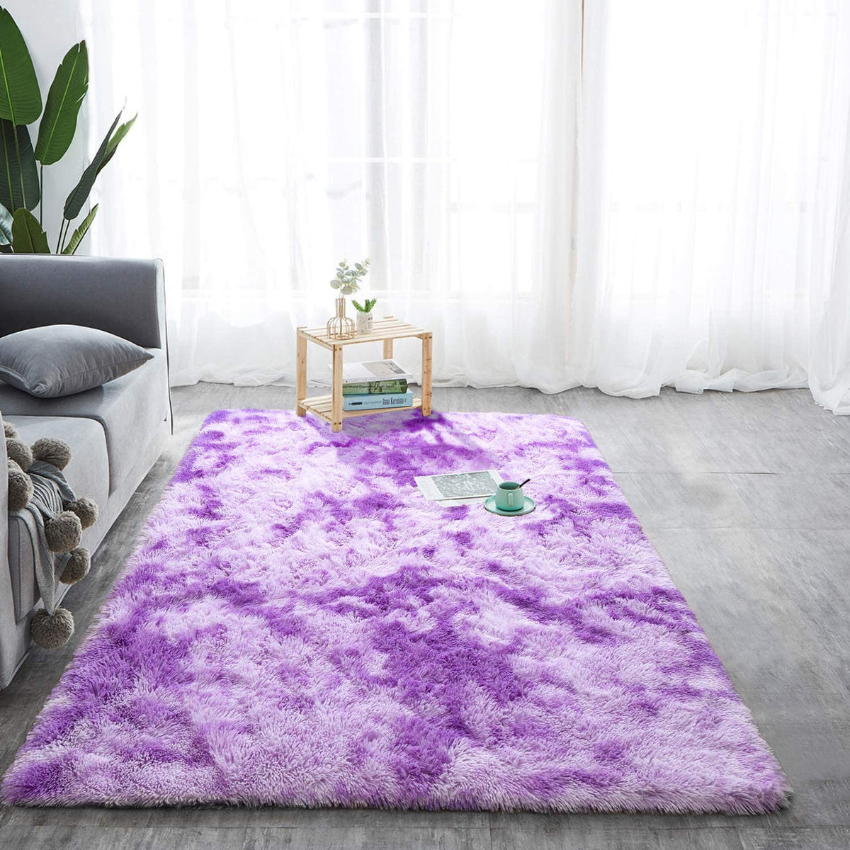 Purple and white tie-dye fluffy rug beside a gray sofa