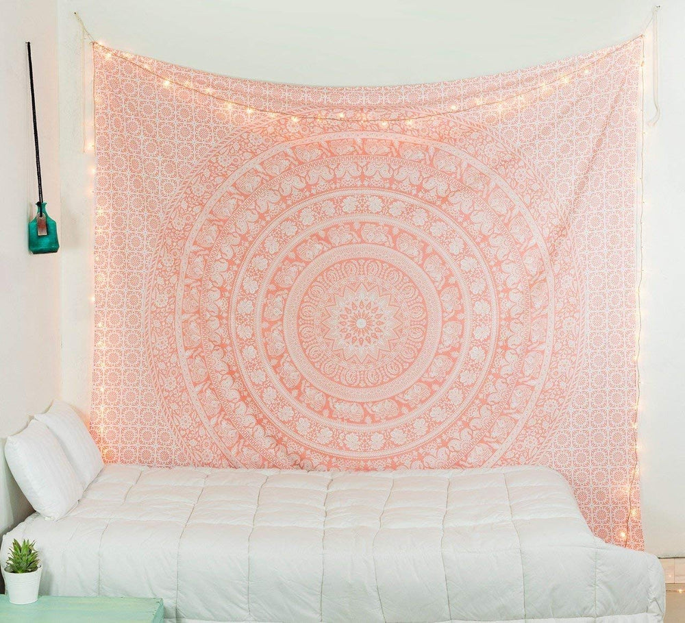Pink elephant mandala tapestry with warm string lights above a white sofa